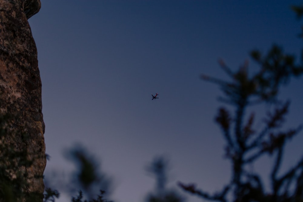 a small plane flying over a large rock