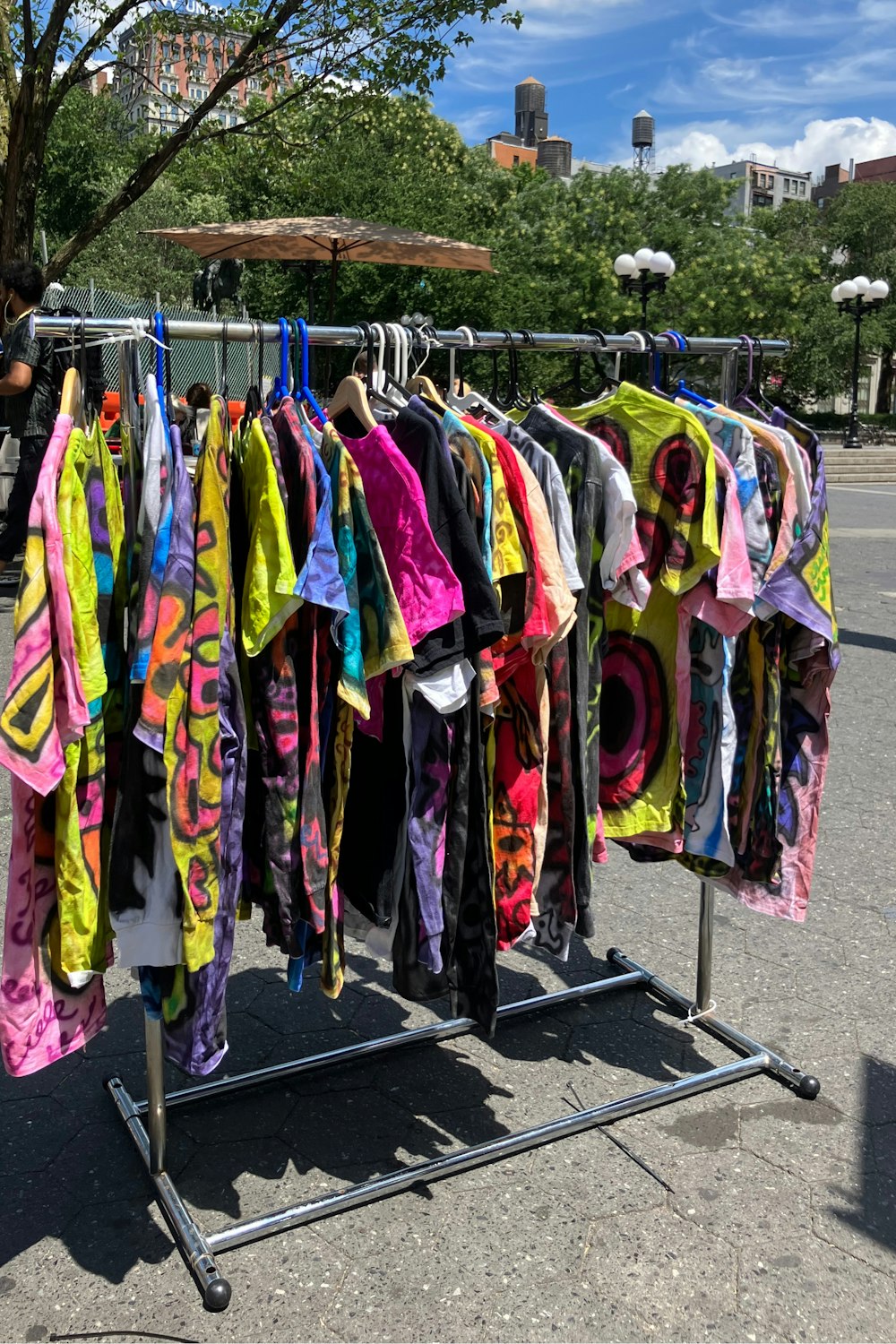 a rack of colorful shirts on a city street