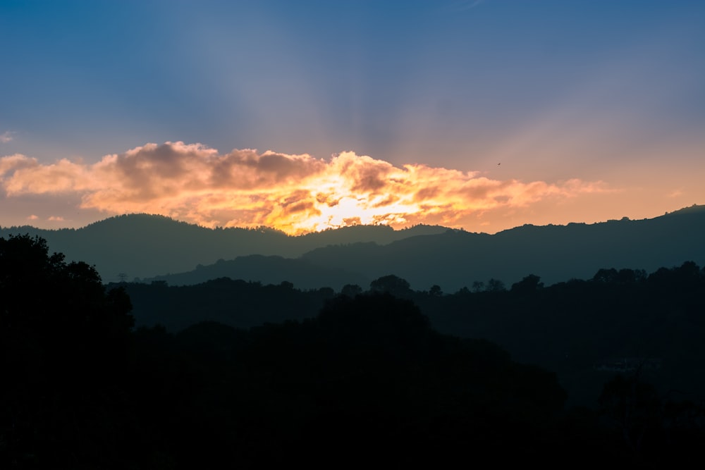 the sun is shining through the clouds over the mountains