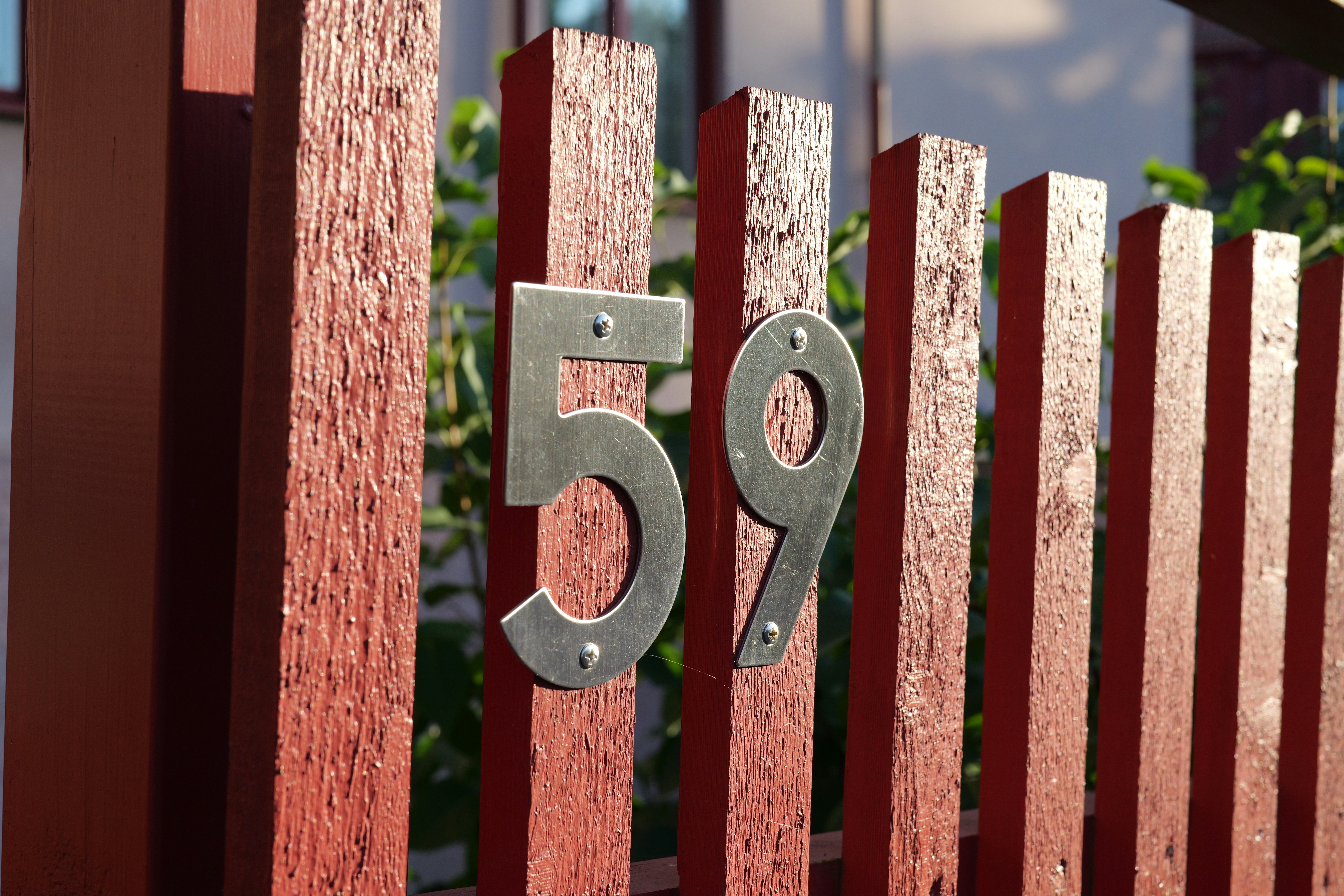 Number 59 in metal on a red wooden gate
