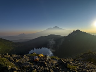 A scenic view of a mountain landscape with a campfire setup in the foreground.