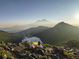 A sleek touisset backpacking tent set up on a rocky mountain ridge at sunrise.