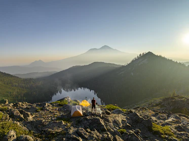 A sleek touisset backpacking tent set up on a rocky mountain ridge at sunrise.