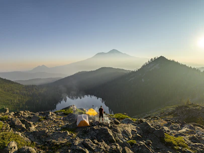 A lightweight backpacking tent set up on a rocky mountain ledge at sunrise