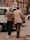 An elderly couple walking together on a city street, holding each other closely. They are wearing casual clothing and appear to be engaged in a leisurely stroll. Surrounding them are parked cars and urban buildings, with a soft, warm ambiance.