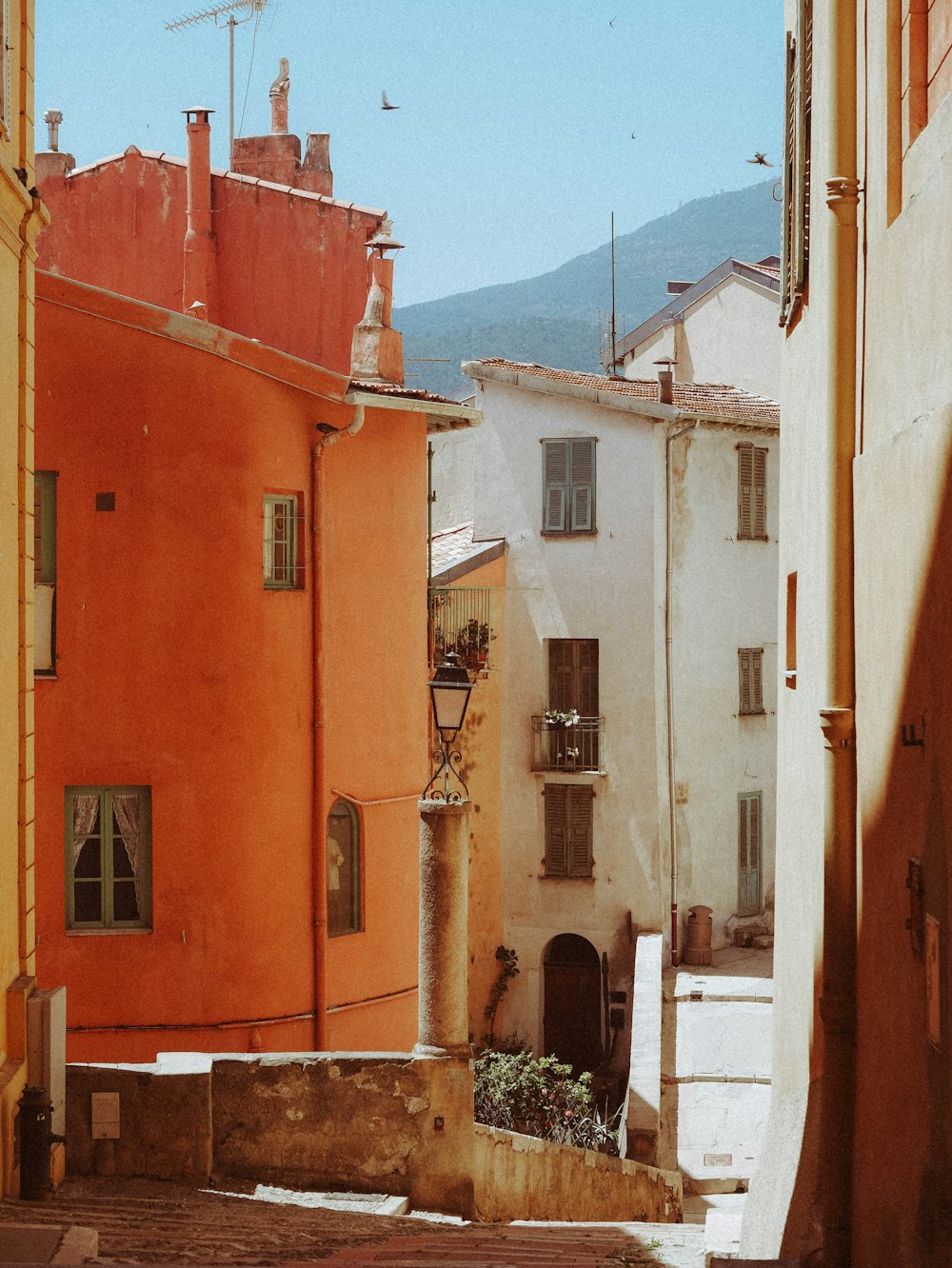 an alley way with buildings and a clock tower in the distance