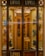 A quaint shop window display featuring an array of colorful leather gloves neatly arranged on a wooden background. The interior is warmly lit, showcasing the elegance and variety of the gloves. The vintage aesthetic of the store is enhanced by the decorative glass panels and wooden frames.