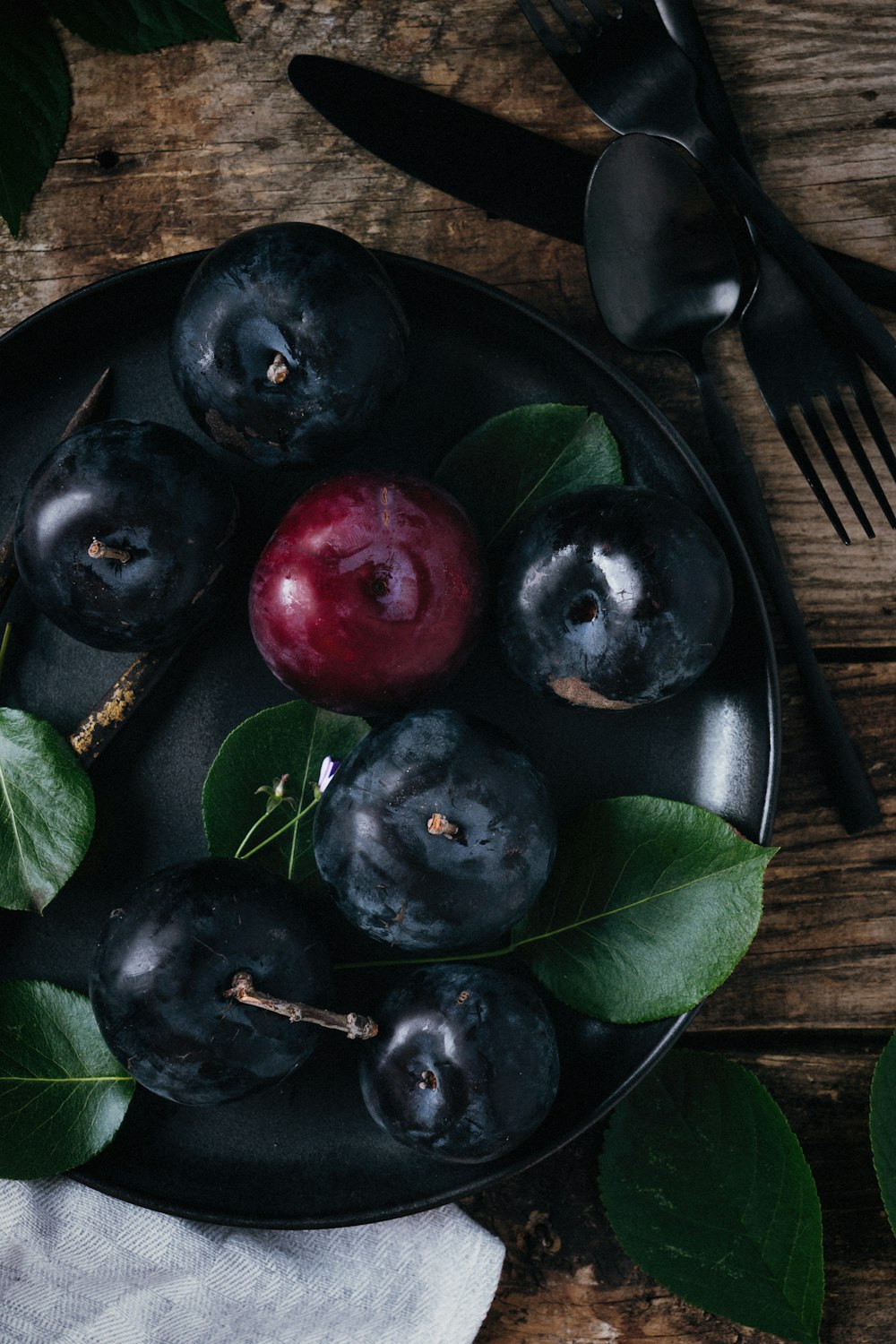 a black plate topped with blueberries and cherries