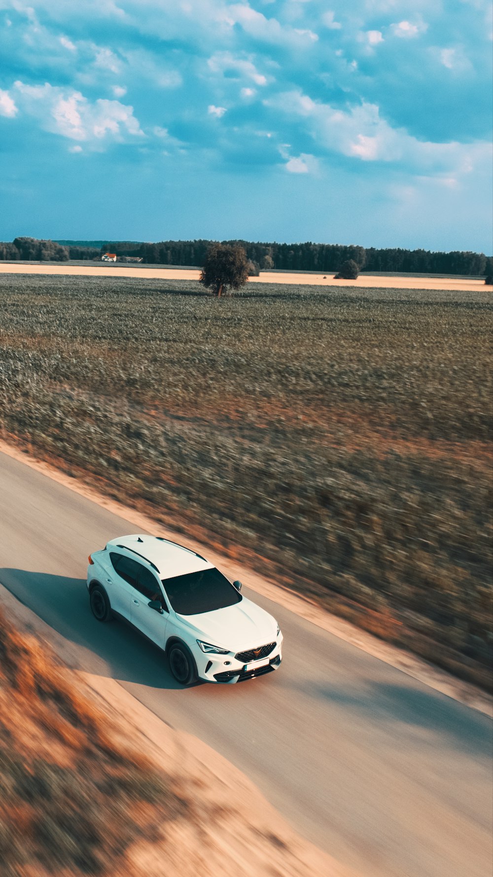 a white car driving down a dirt road