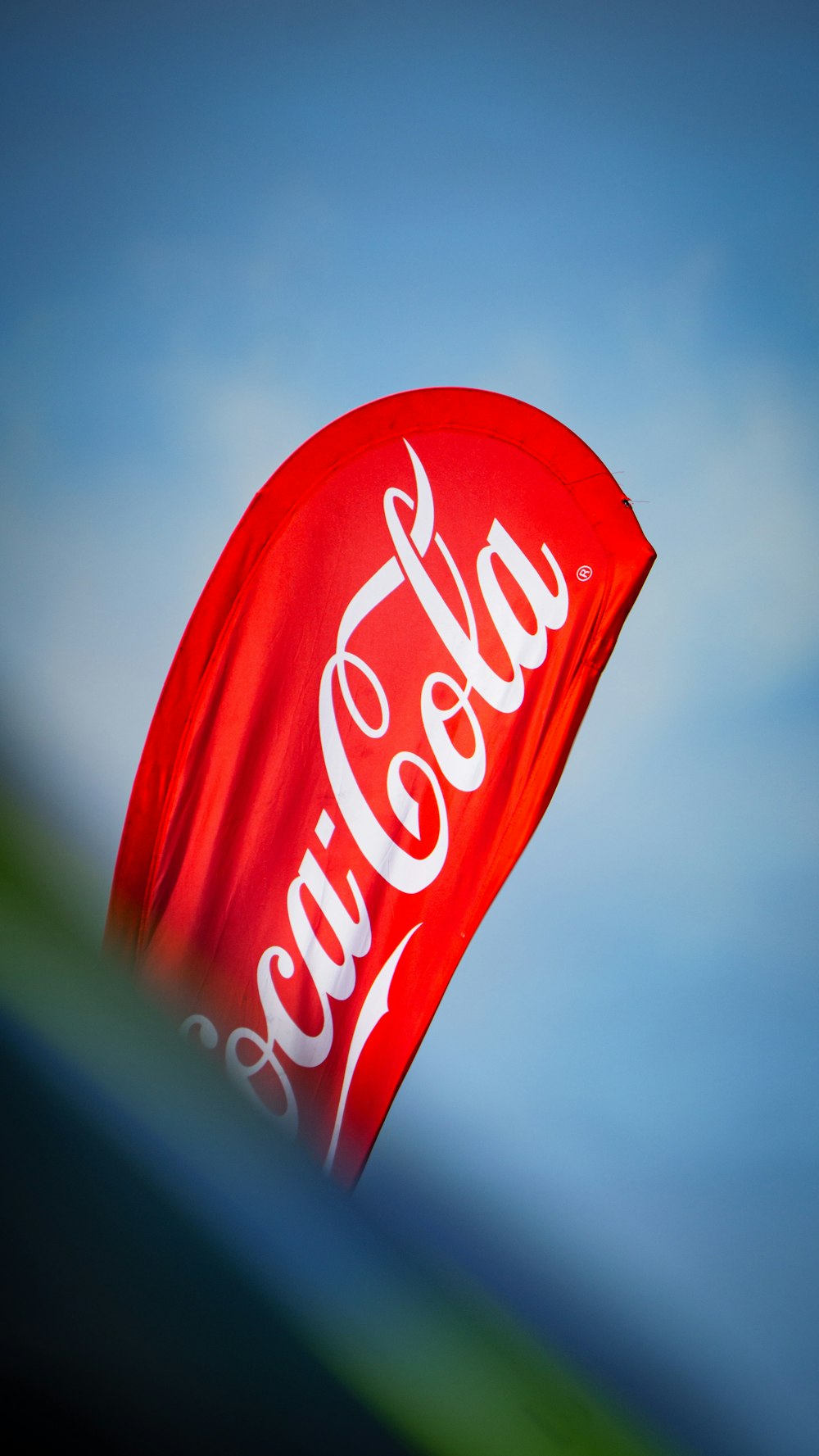 a coca - cola kite is flying in the sky
