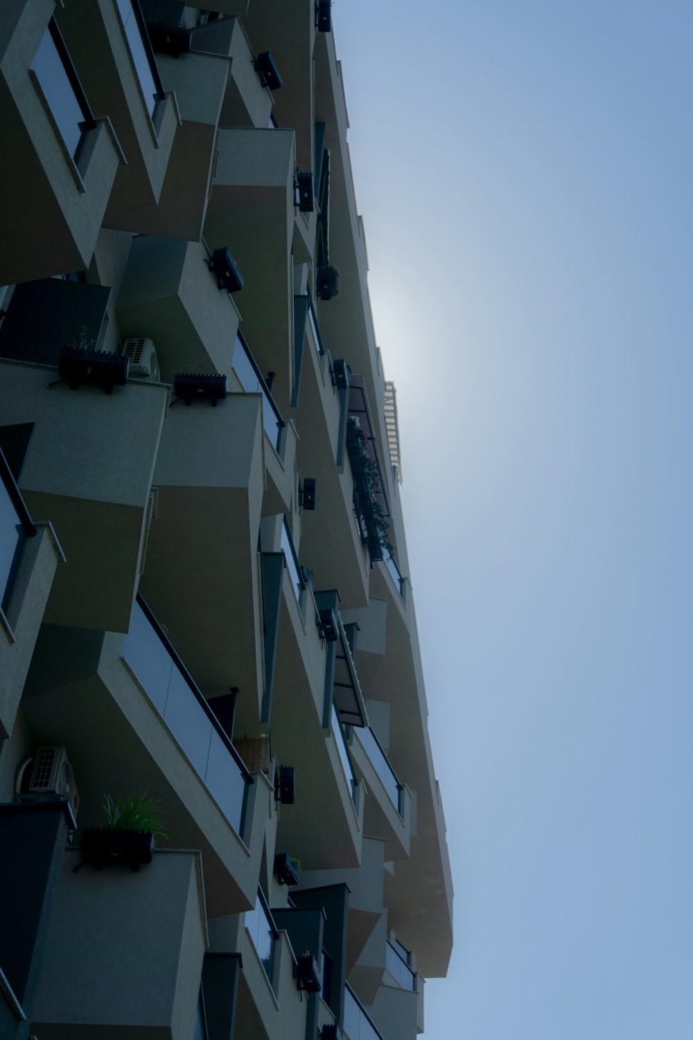 a tall building with windows and balconies against a blue sky