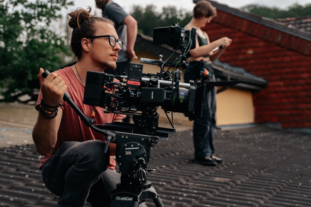 a man sitting on top of a roof next to a camera