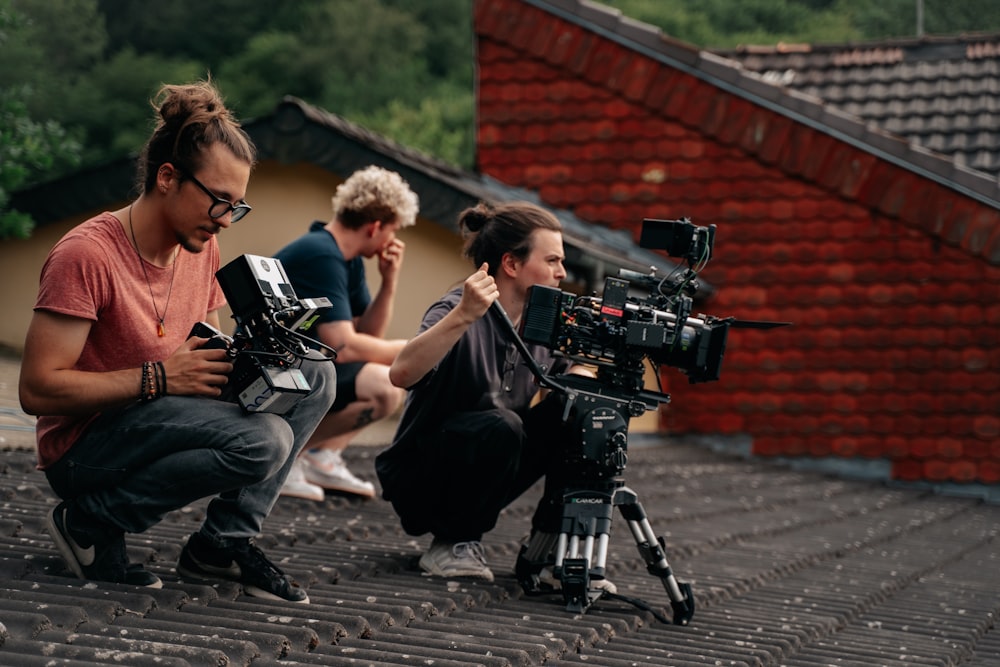 three people sitting on a roof with a camera