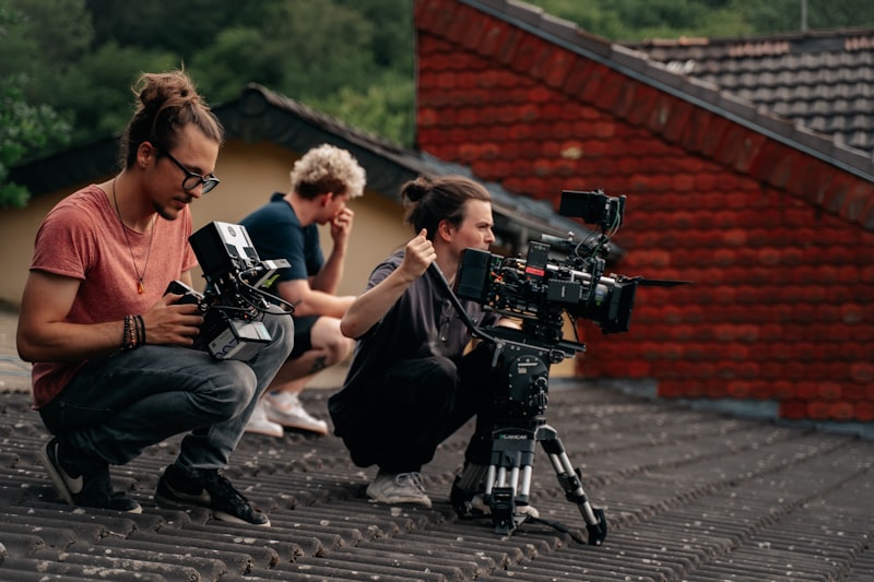 three people sitting on a roof with a camera