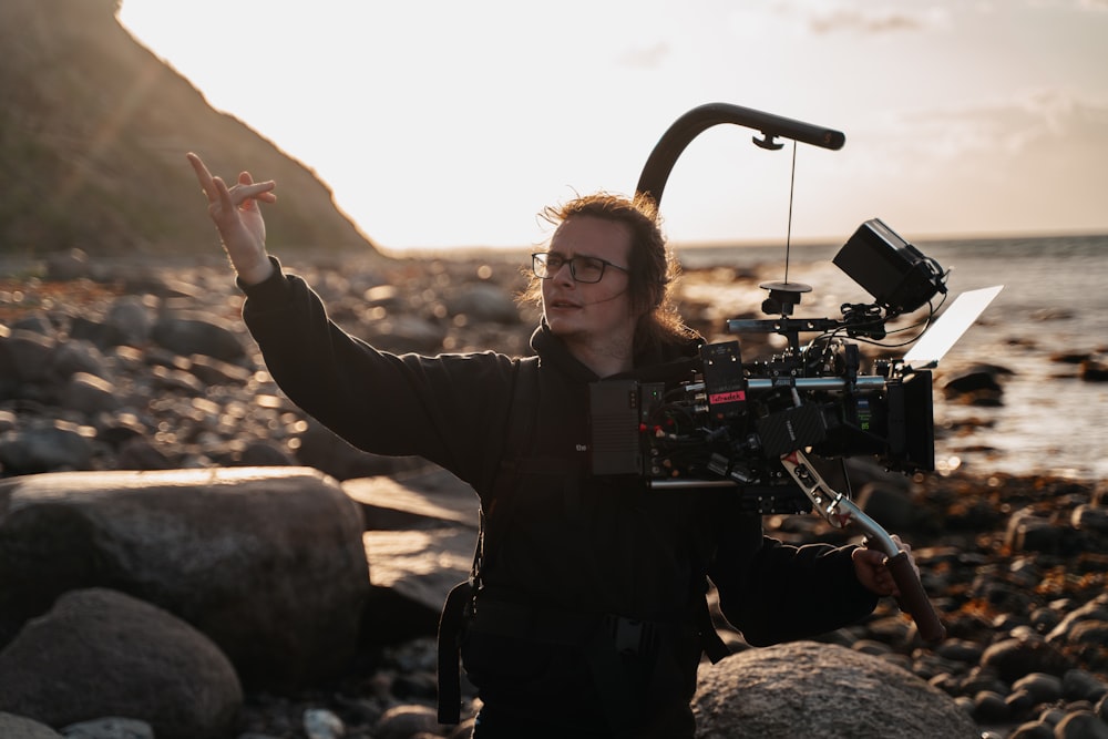 a woman standing on a rocky beach holding a camera