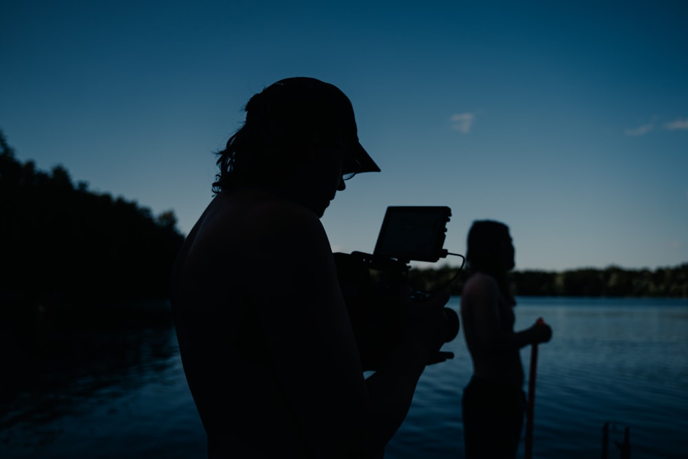 a man holding a camera next to a body of water