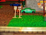 Close-up of a detailed 1/64 scale diorama featuring a miniature street scene with tiny vehicles and buildings.