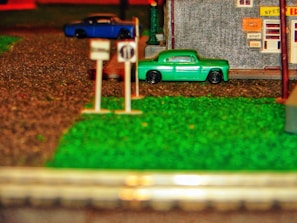 Close-up of a detailed 1/64 scale diorama featuring a miniature street scene with tiny vehicles and buildings.