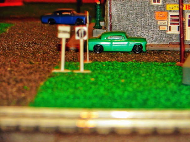 A detailed diorama featuring classic muscle cars parked on a miniature street