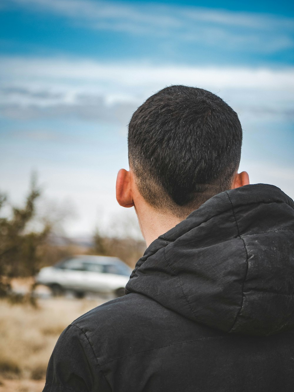 a man in a black jacket standing in a field