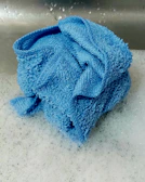 Close-up of a natural fiber dishcloth draped over a kitchen sink faucet.