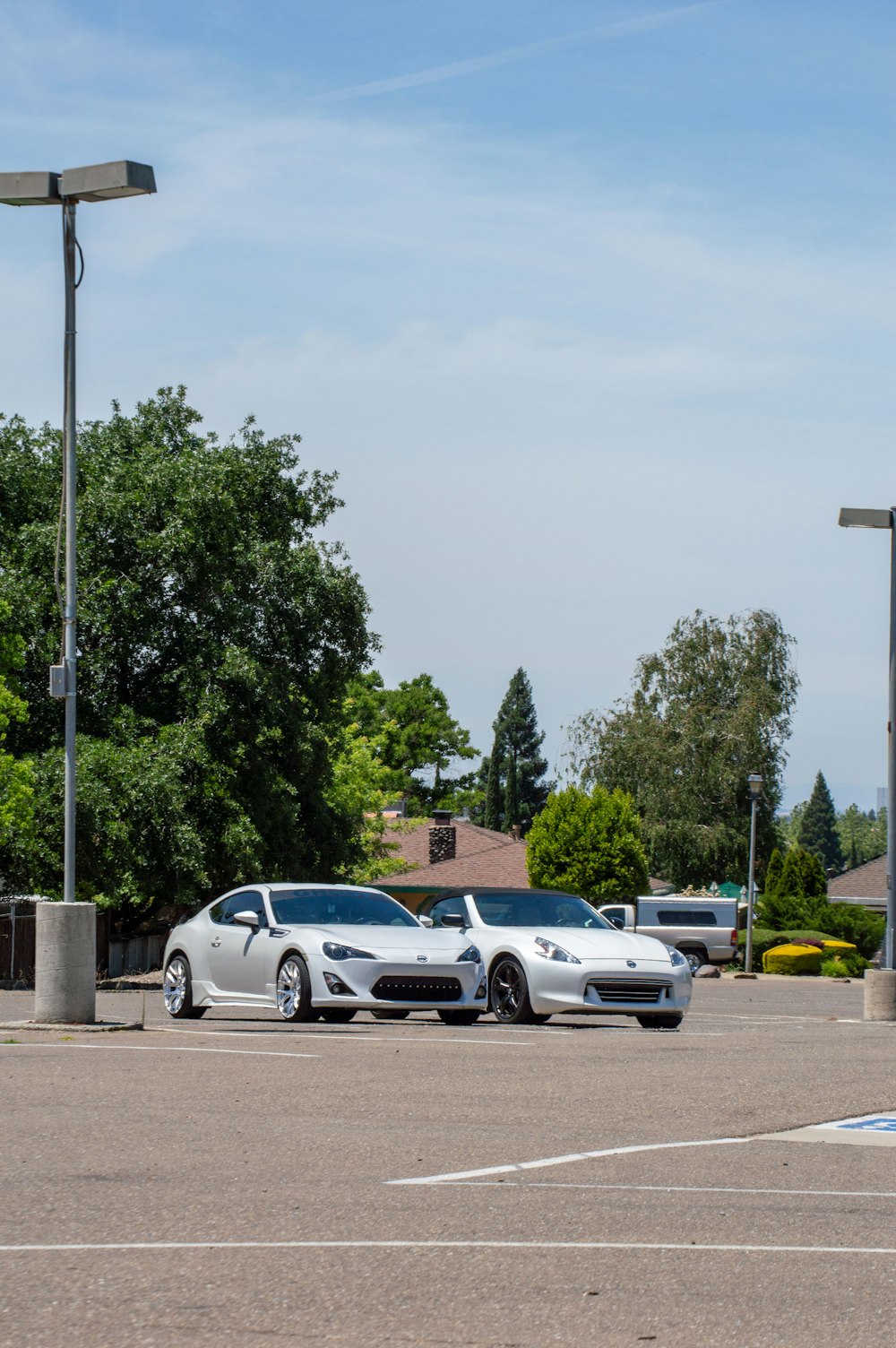 Zwei weiße Sportwagen auf einem Parkplatz geparkt