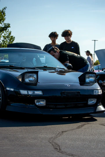 a group of young men standing next to a parked car