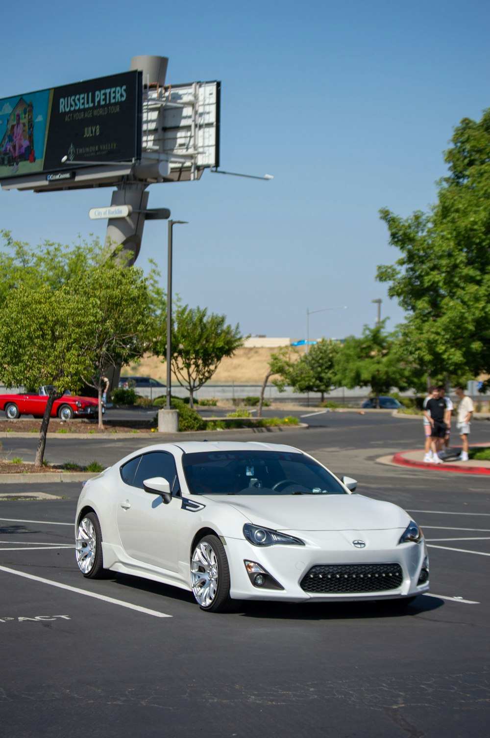 a white sports car parked in a parking lot