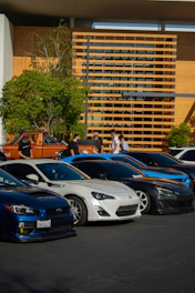 A sleek lineup of well-maintained vehicles parked in front of a modern office building.