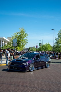 a purple car parked in front of a crowd of people