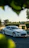 A shiny white Porsche parked in a residential driveway, freshly detailed by a professional technician.
