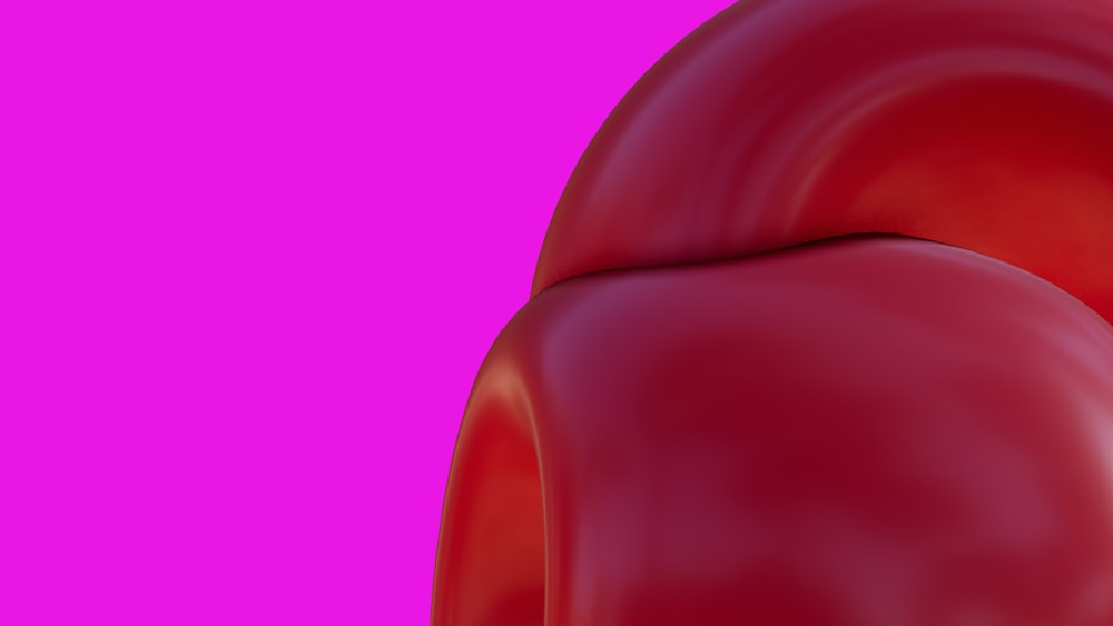 a close up of a red object on a pink background