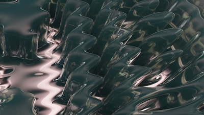 Abstract, fluid, glass-like structures with a smooth, reflective surface and undulating shapes create a sense of motion and fluidity.