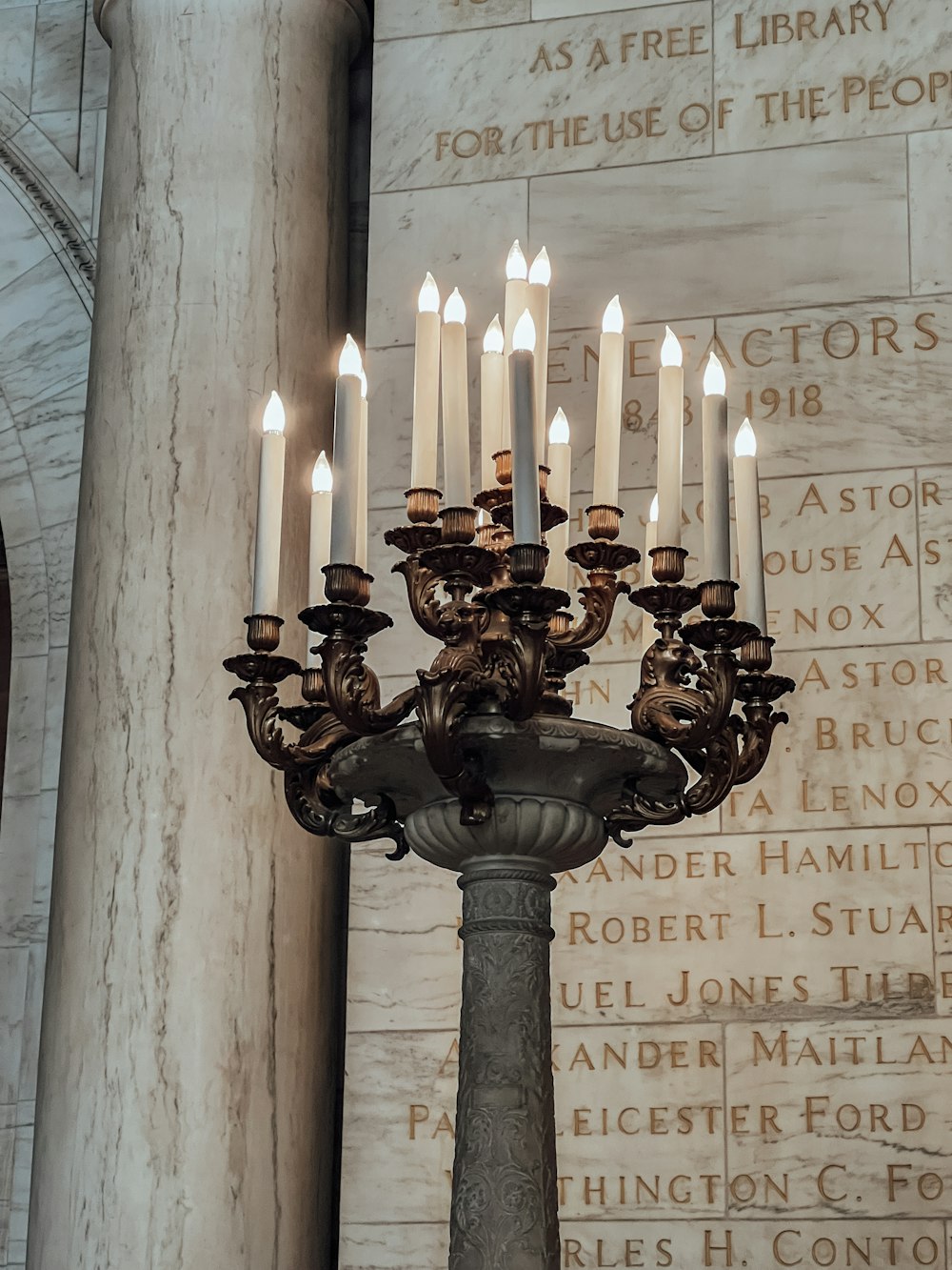 a chandelier with many lit candles in front of a wall