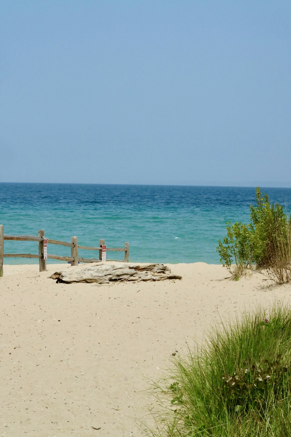 a sandy beach with a wooden fence and ocean in the background