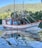 A colorful fishing boat sails along a calm body of water with lush green hills in the background. The boat, named Vitor Gabriel, features vibrant orange and blue accents and intricate rigging. The reflection of the boat creates a visually captivating pattern on the water's surface.