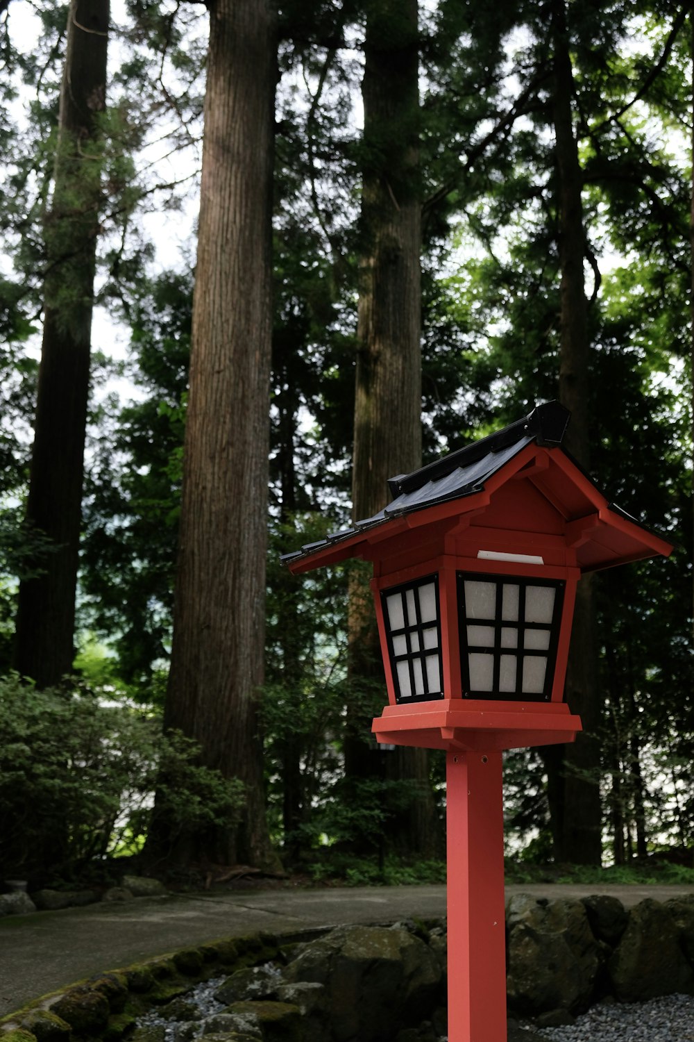 a red bird house in the middle of a forest