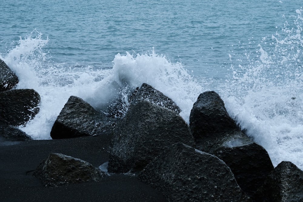 a wave crashes on rocks near the ocean