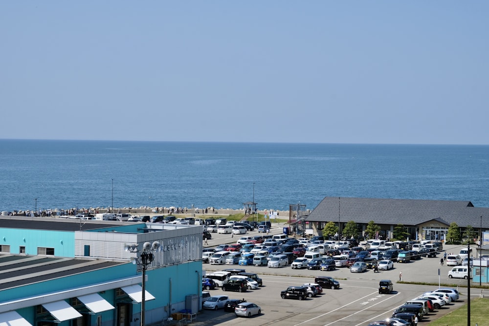 a parking lot next to the ocean with cars parked in it