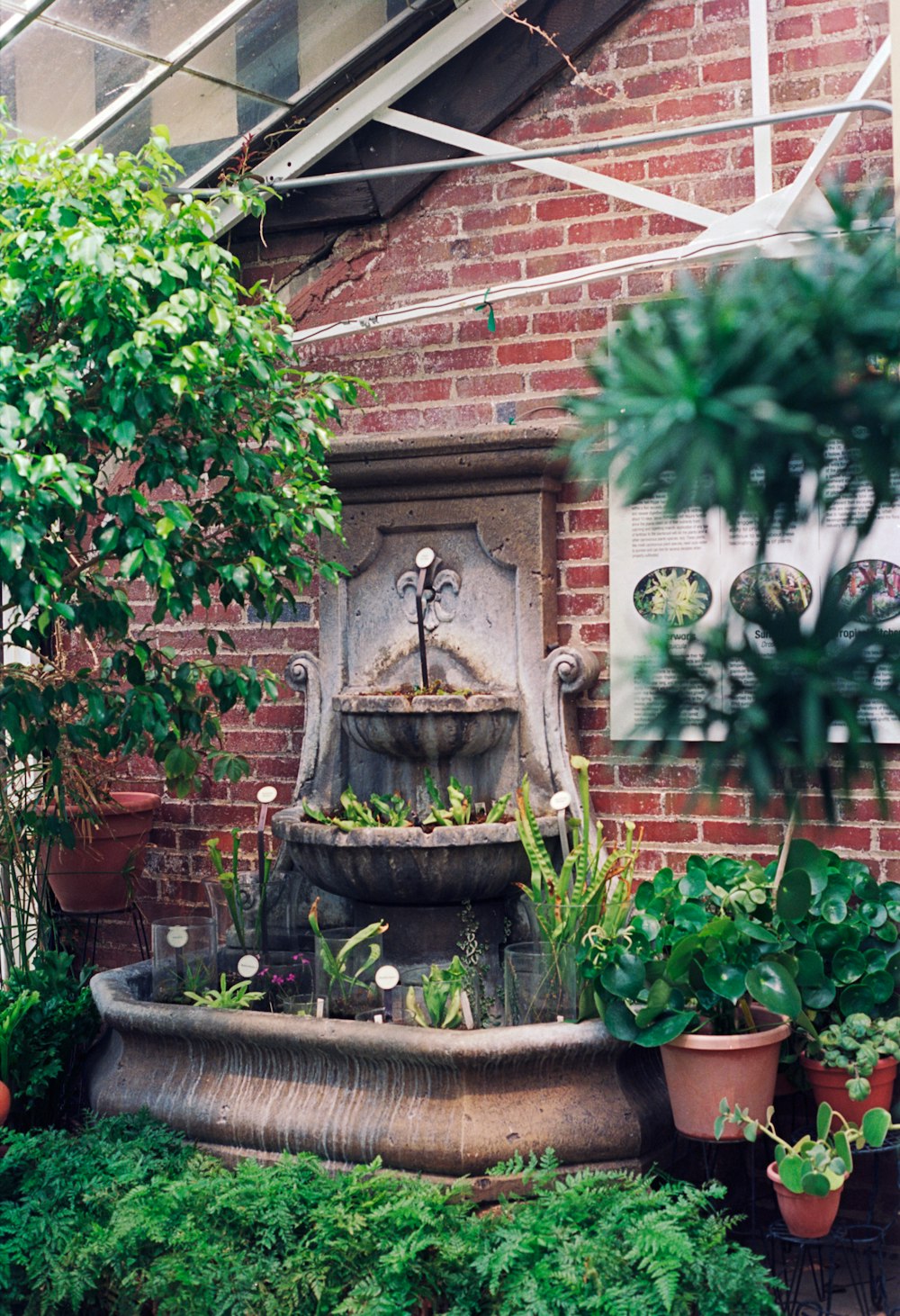 a brick building with a fountain surrounded by plants