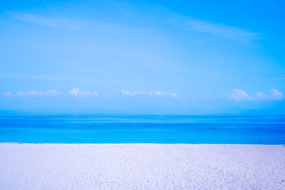 a bench sitting on top of a sandy beach next to the ocean