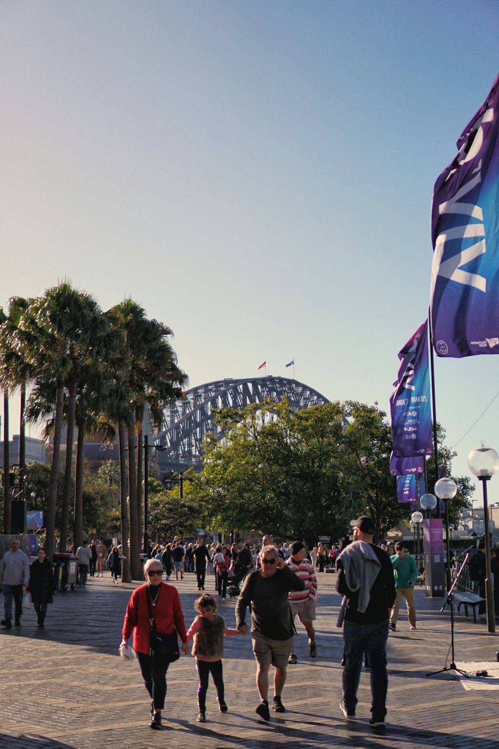 a group of people walking down a street next to a bridge