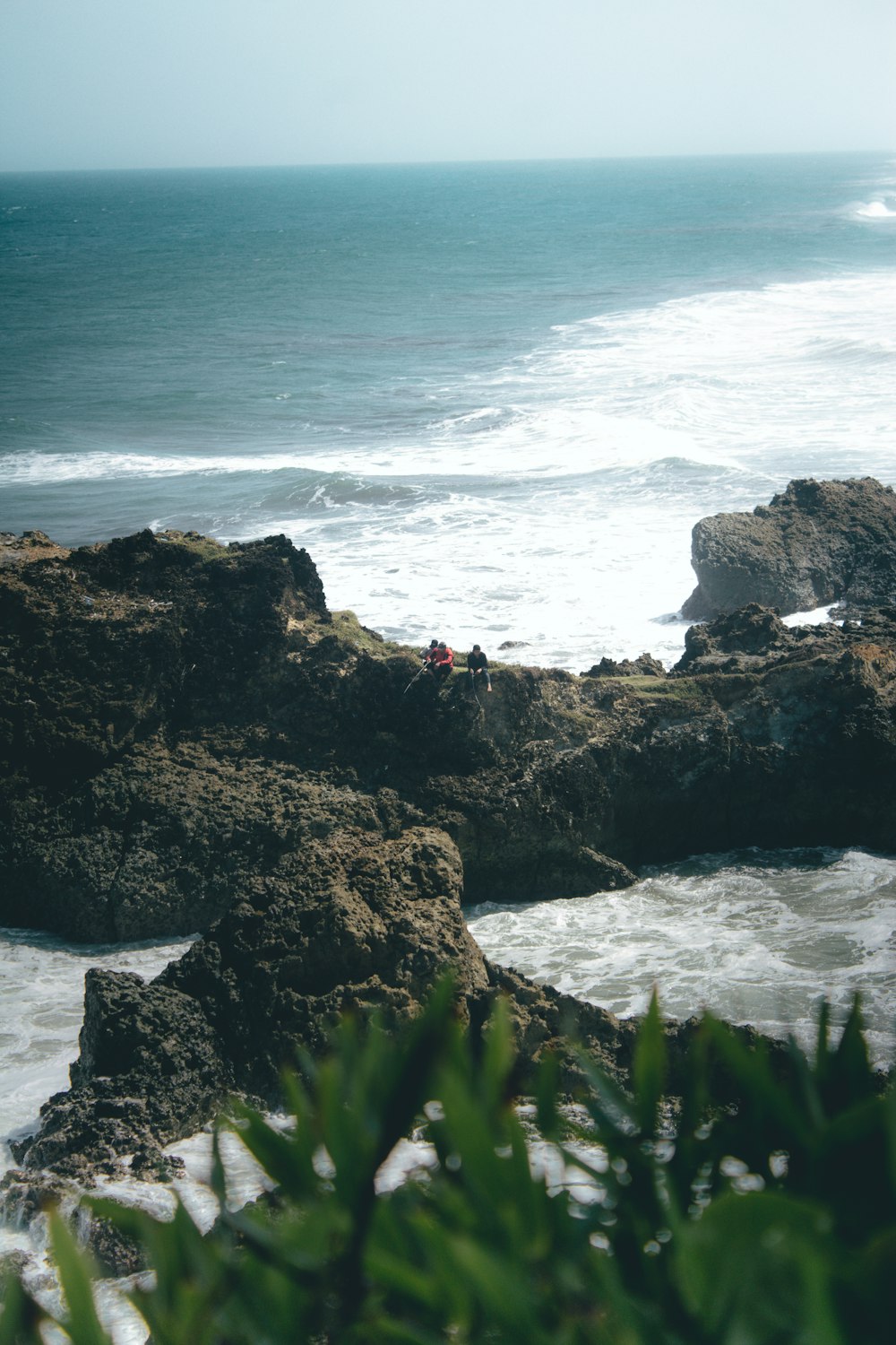 a couple of people sitting on top of a rocky beach