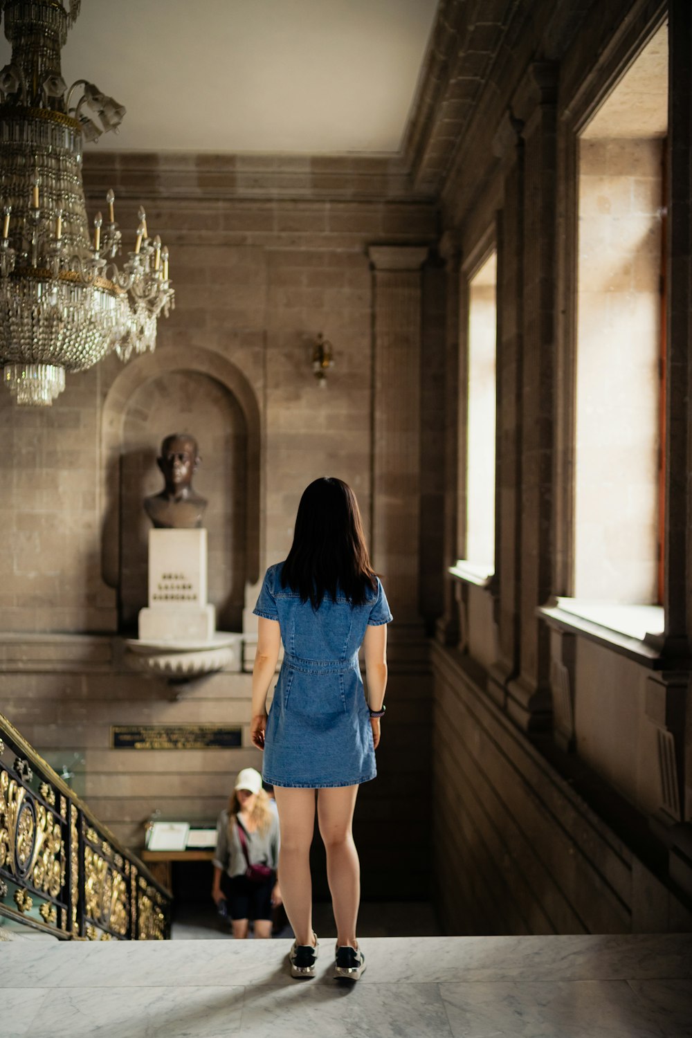 a woman in a blue dress walking down a staircase