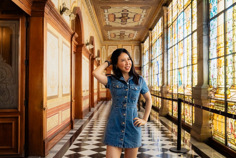 a woman in a denim dress standing in a hallway