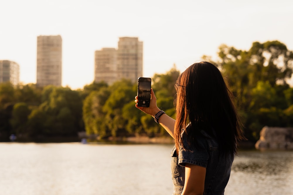 a woman taking a picture of a city skyline with her cell phone