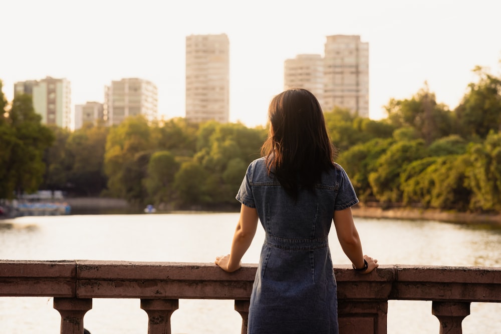 a woman standing on a bridge looking at the water