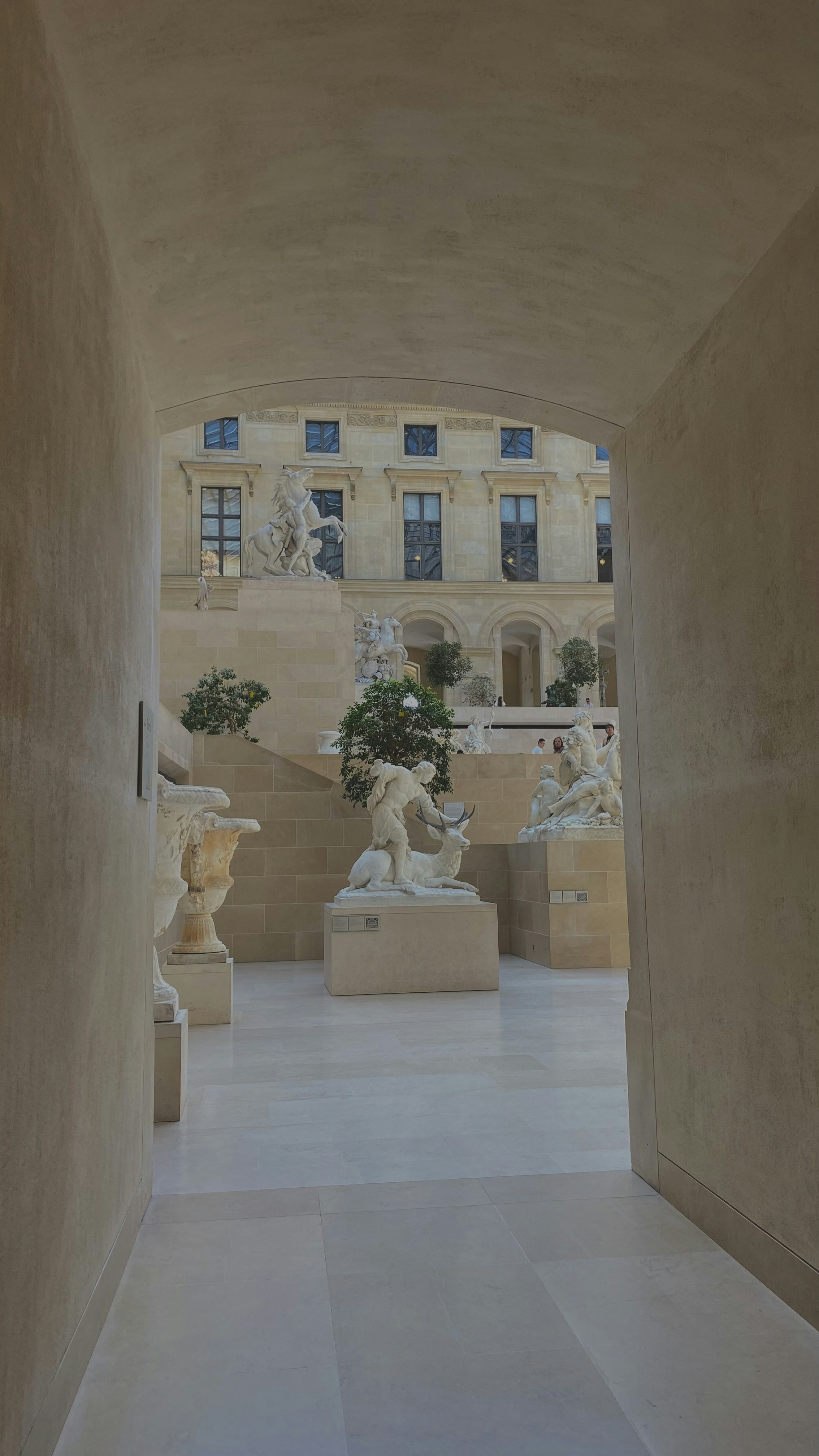 a hallway with statues and a building in the background