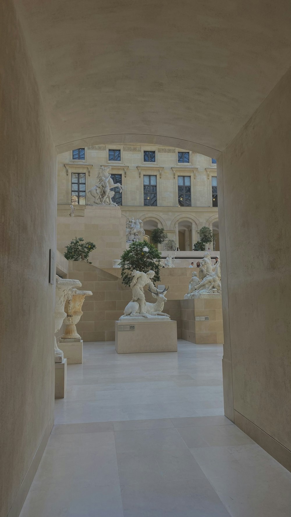 a hallway with statues and a building in the background