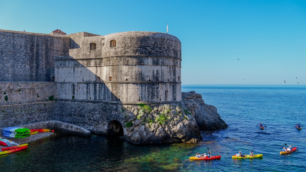 a group of people in kayaks on the water near a castle